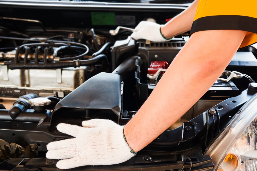 A professional changing a car battery replacement onsite.